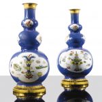 A pair of gilt-bronze mounted Chinese porcelain gourd shaped bottles, Kangxi (1662-1722), the gilt-bronze mounts 18th century the central cartouche decorated with fabric, vases, flowers and animals, against a blue ground; (regilt)