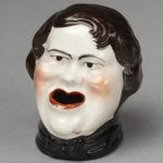 Ink pot of bone china in the form of a grotesque head of a beardless man