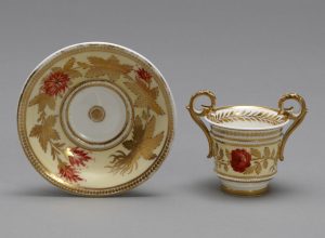 Two-handled cup and saucer of porcelain painted in colours and gilded