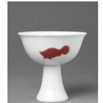 Porcelain stem cup with high foot, painted in underglaze copper red with three stylised fish, equally distanced. A six-character mark in a double circle is painted in underglaze blue inside the foot.